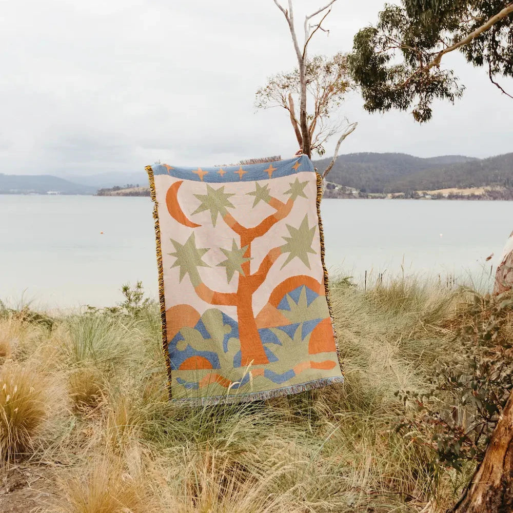 Colorful throw blanket with abstract design of a tree in the desert