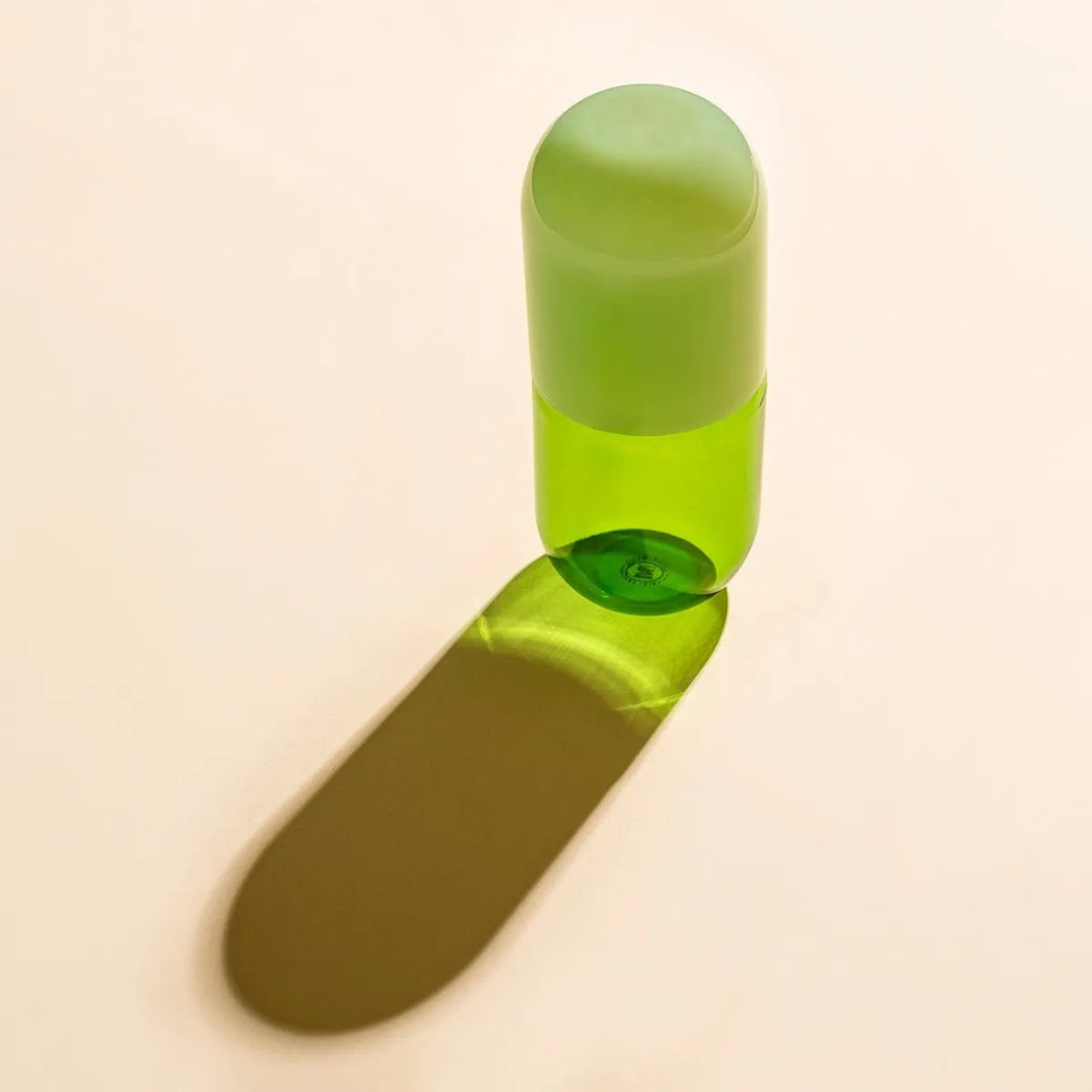 Green glass bottle with green bottle cap on a beige background