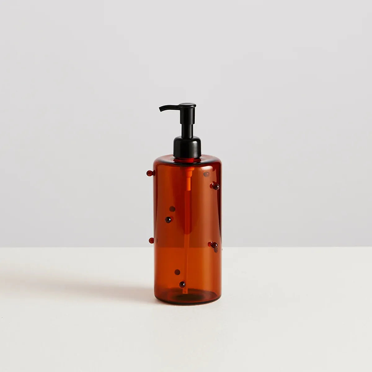 Brown bottle with black pump on a light gray background