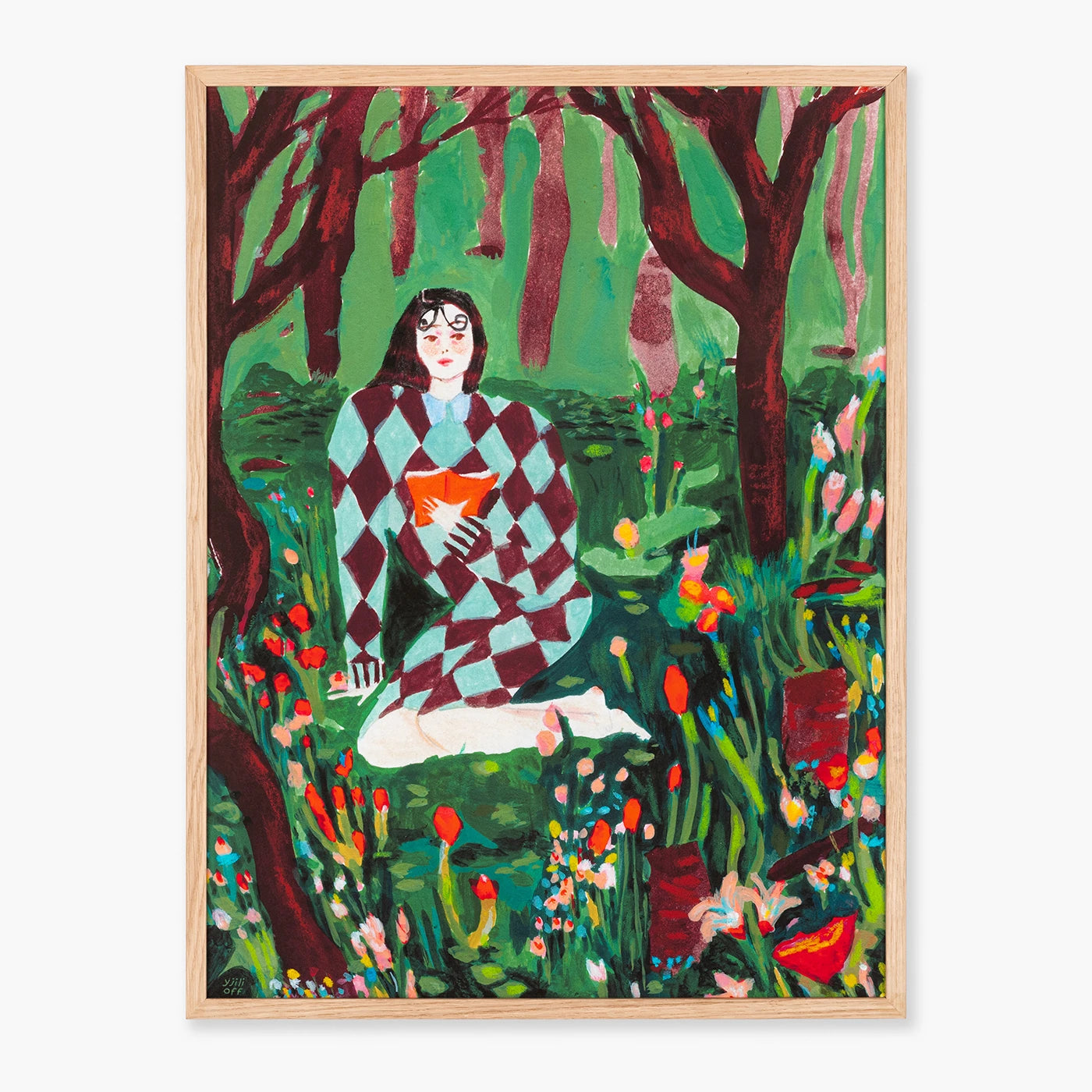 Wall art framed in light oak timber featuring a stylized illustration of a woman in a green and burgundy diamond-patterned sweater sitting in a forest clearing with flowers, set against a light gray background.
