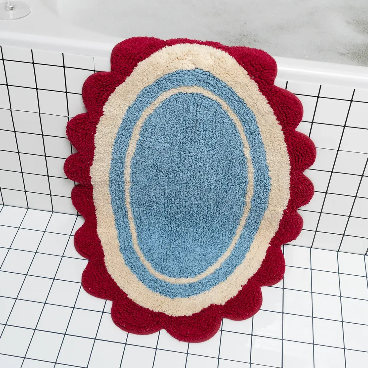 Decorative bath mat with concentric circles in red, beige, and blue on a grid background