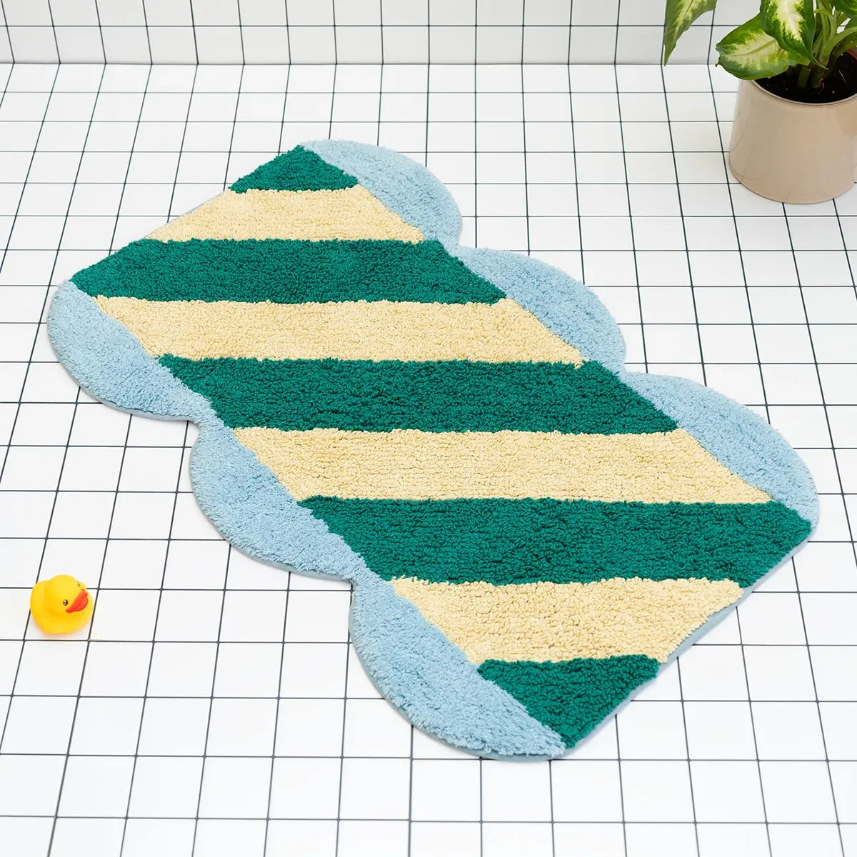 Striped bath mat with green and beige stripes on a grid background
