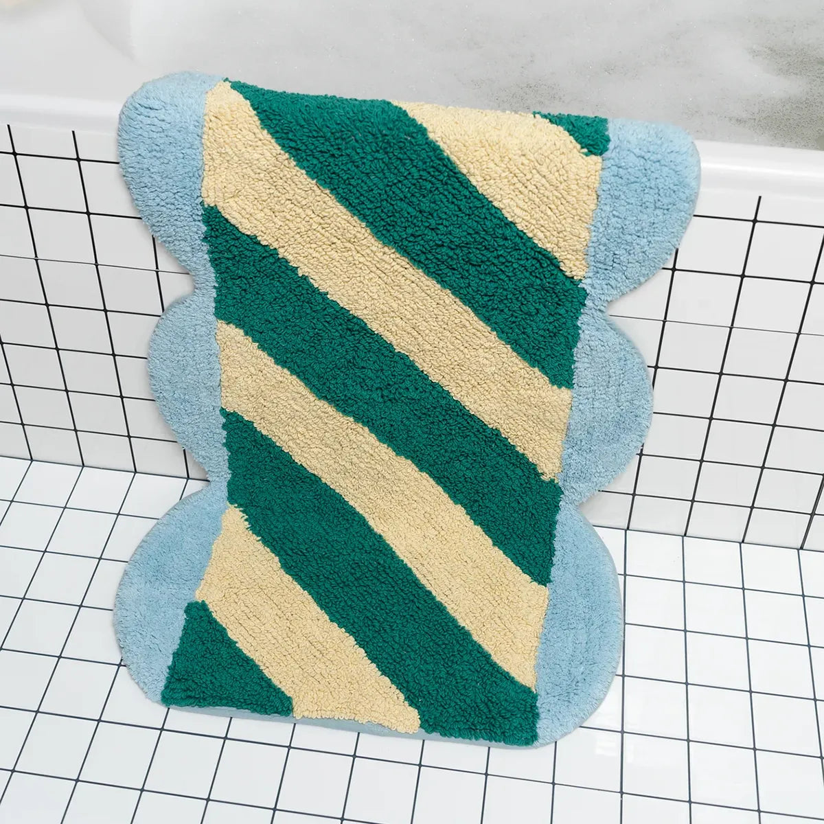 Rectangular bath mat with green and beige zigzag pattern on a grid background