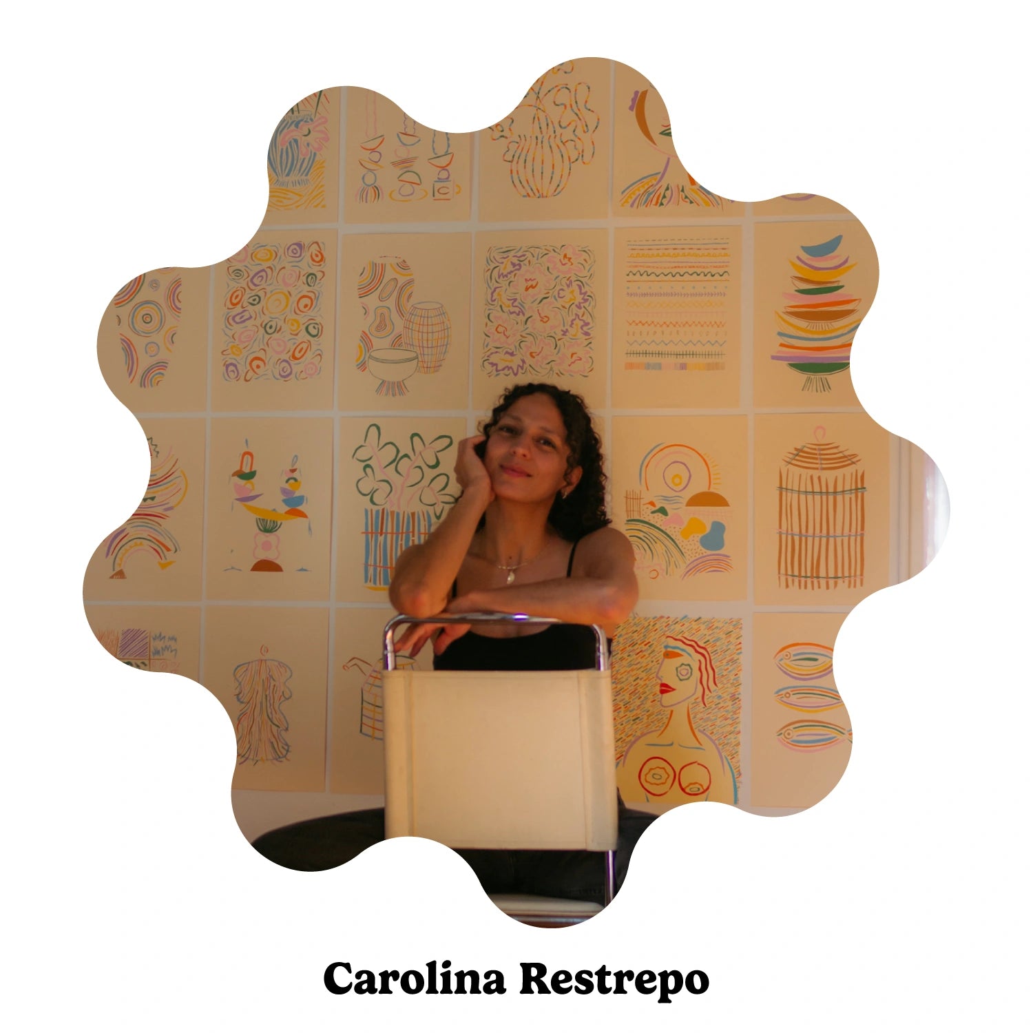 Spanish artist Carolina Restrepo seated in a chair against a background covered in wall art.