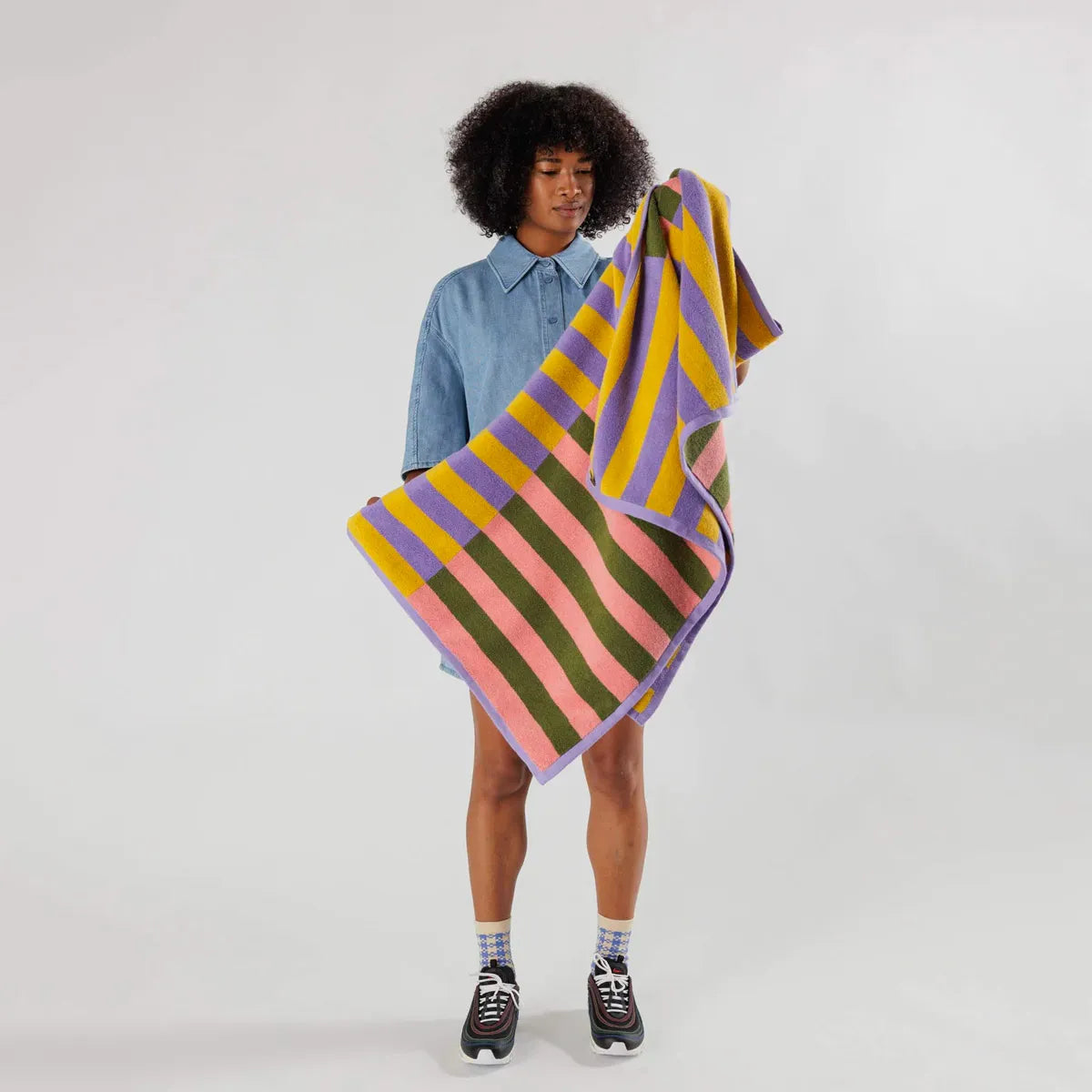 Person holding a colorful striped towel against a plain background
