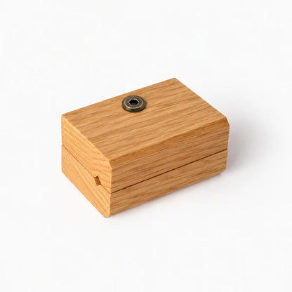 Close up showing one blanket hanger clip in a beautiful oak grain. A round metal screw on top, set against a plain white background.