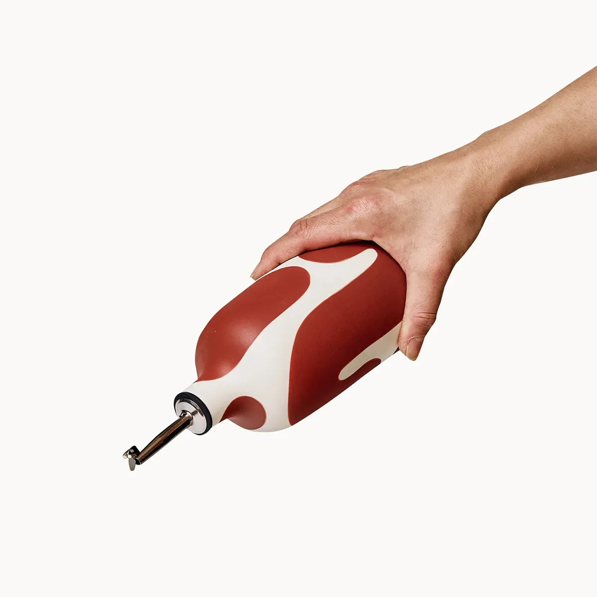Hand holding a red and white bottle against a white background