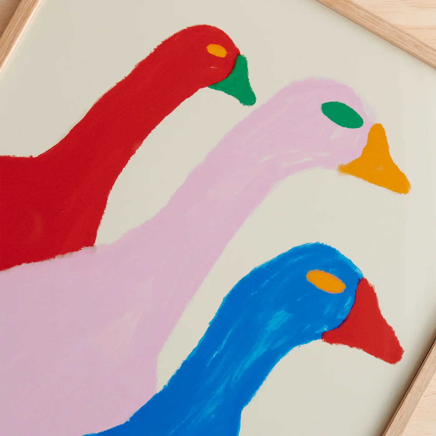 A close-up of a colorful abstract art print depicting three stylized goose-like heads in red, light pink, and blue, with green, yellow, and orange accents on a cream background.