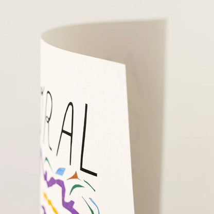 A close-up of a white art print showing partial black text and colorful abstract line art on a light neutral background.