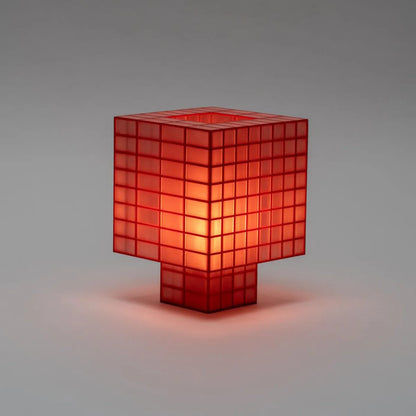 Illuminated Ridezign Tesser 8:3 table lamp in Cherry with an open top, made from a red grid over warm orange panels, casting a soft glow against a neutral grey-brown background.