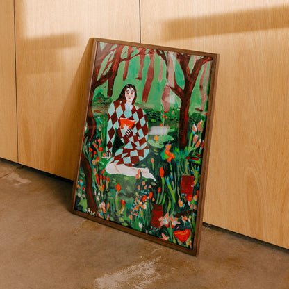 Framed wall art leaning against a light wood cabinet on a concrete floor. The art print depicts a seated woman in a red-and-white checkered dress surrounded by green foliage, red trees, and orange flowers.