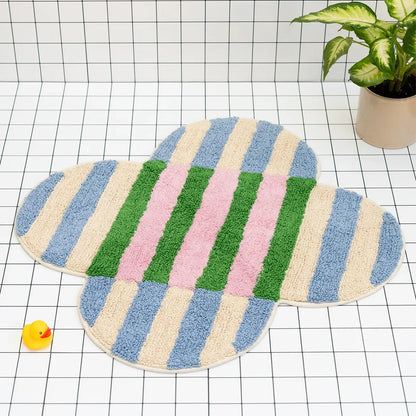 Colorful striped bath mat on a grid background with a rubber duck and plant.