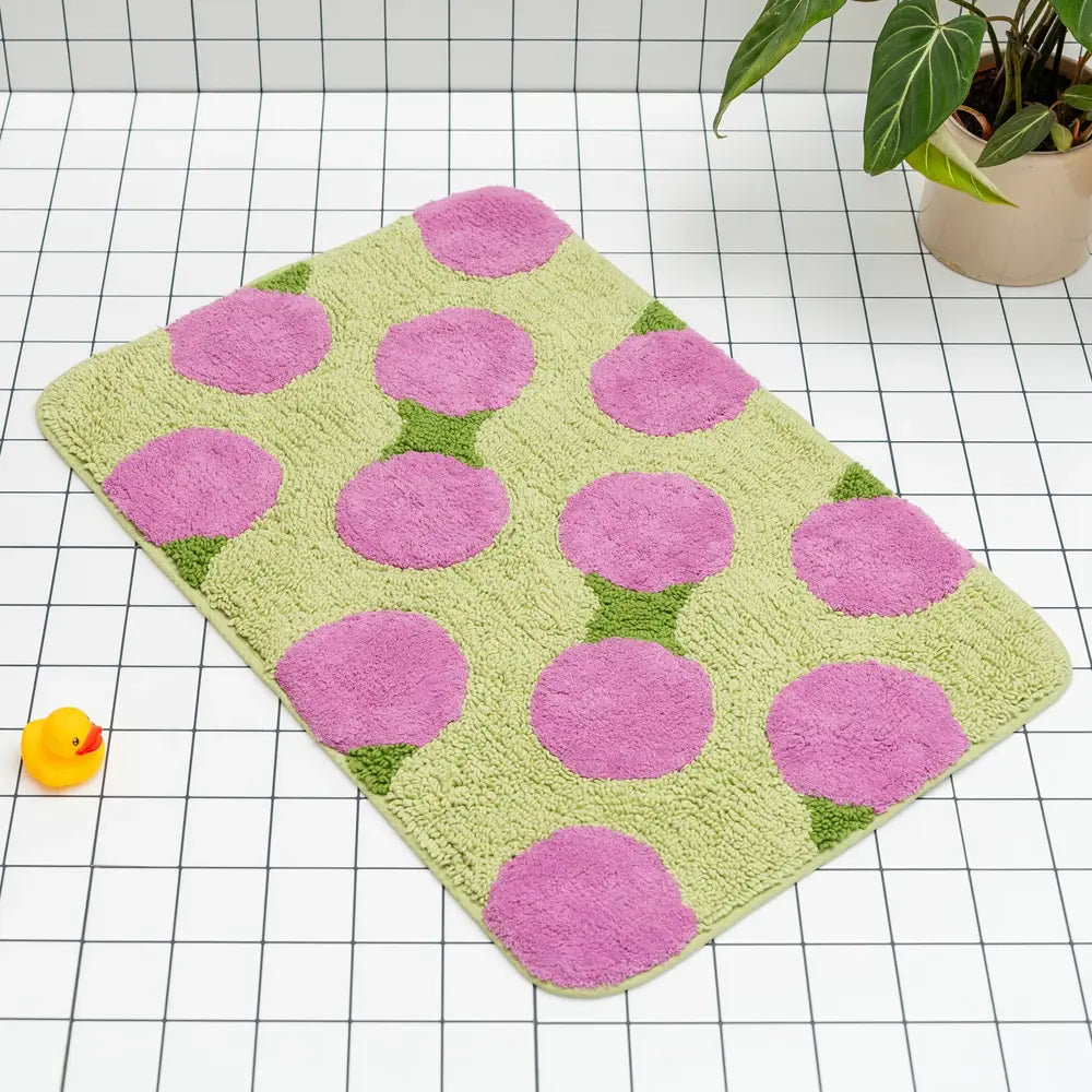 Green bath mat with pink circles on a checkered floor