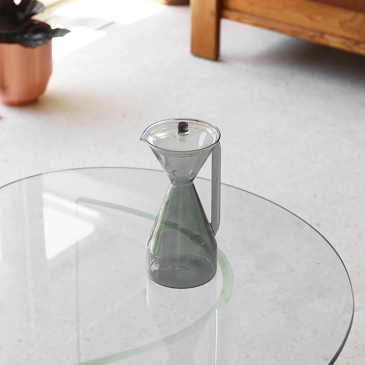 Gray glass carafe on a round glass table 