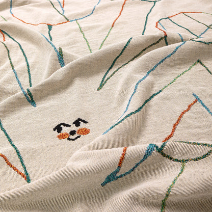 Close-up of embroidered fabric with a face design on a beige background