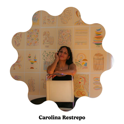 Spanish artist Carolina Restrepo seated in a chair against a background covered in wall art.