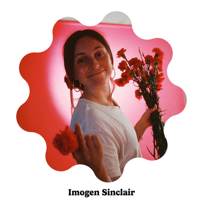 Portrait of English artist Imogen Sinclair holding orange flowers against a pink and red background, presented in a scalloped circular frame with the text &